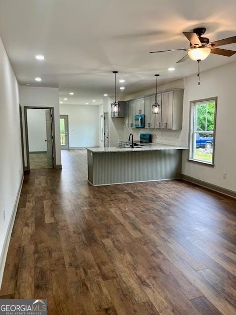 kitchen with dark wood finished floors, light countertops, gray cabinetry, stainless steel microwave, and recessed lighting