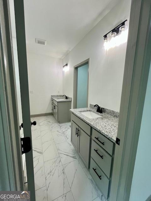 bathroom featuring visible vents, a sink, marble finish floor, and two vanities