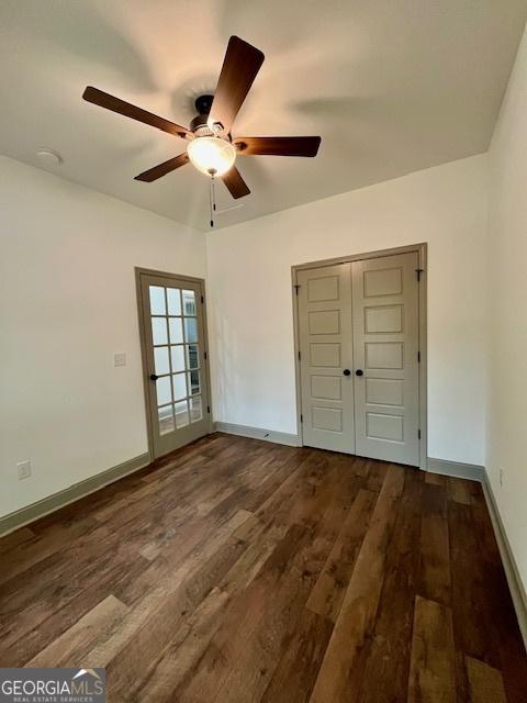 interior space featuring dark wood-style flooring, ceiling fan, and baseboards