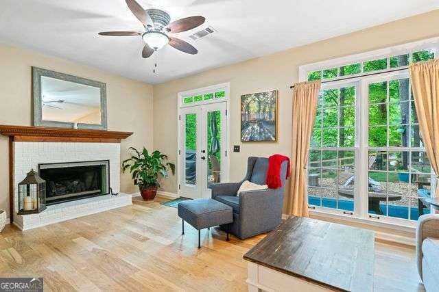 3376 Hickory Ln, Powder Springs, GA 30127 - living area featuring a brick fireplace, a ceiling fan, baseboards, light wood-type flooring, and visible vents