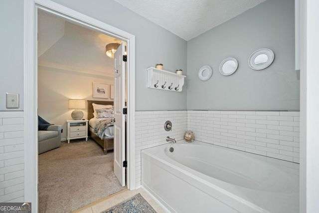 3376 Hickory Ln, Powder Springs, GA 30127 - bathroom featuring tile patterned flooring, ensuite bathroom, and a garden tub