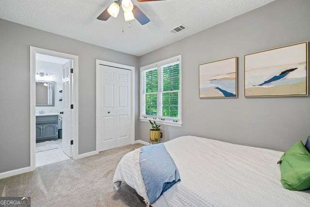 3376 Hickory Ln, Powder Springs, GA 30127 - carpeted bedroom with visible vents, baseboards, ceiling fan, connected bathroom, and a textured ceiling