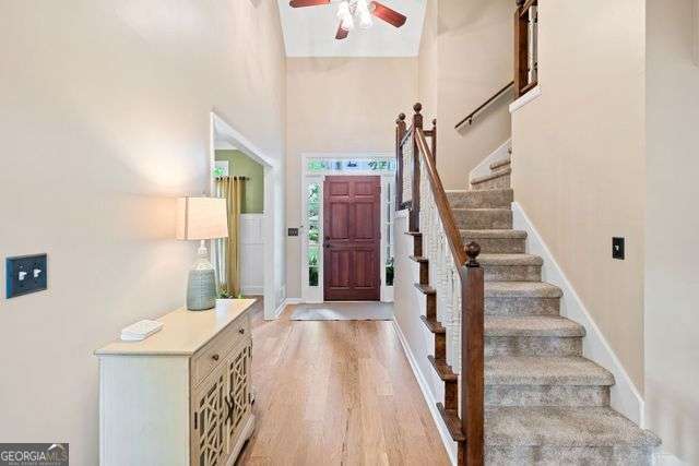 3376 Hickory Ln, Powder Springs, GA 30127 - foyer entrance with light wood-style flooring, a ceiling fan, baseboards, a towering ceiling, and stairway