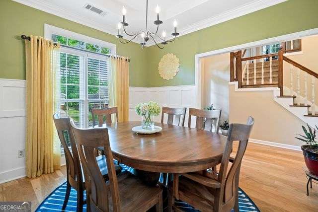 3376 Hickory Ln, Powder Springs, GA 30127 - dining space with visible vents, ornamental molding, a decorative wall, and an inviting chandelier