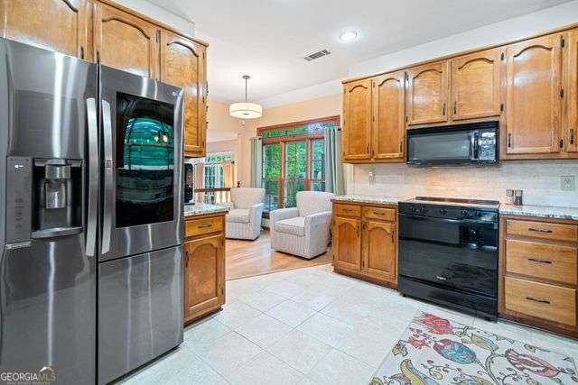 3376 Hickory Ln, Powder Springs, GA 30127 - kitchen with visible vents, light countertops, black appliances, and tasteful backsplash