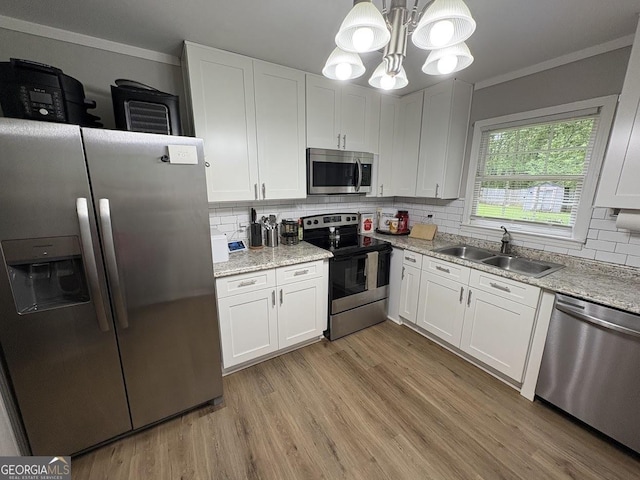 kitchen with a sink, crown molding, stainless steel appliances, and white cabinetry