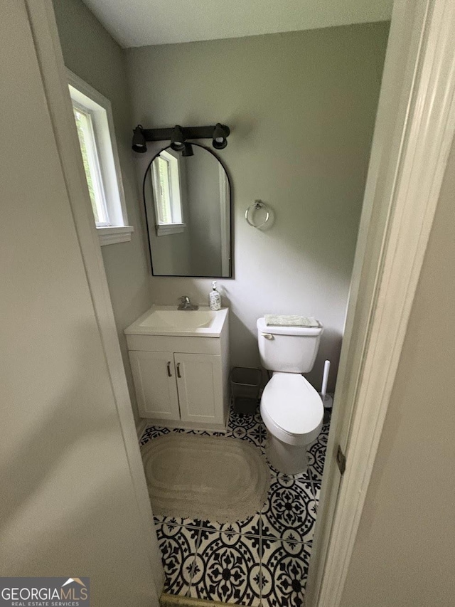 half bath featuring toilet, tile patterned flooring, and vanity