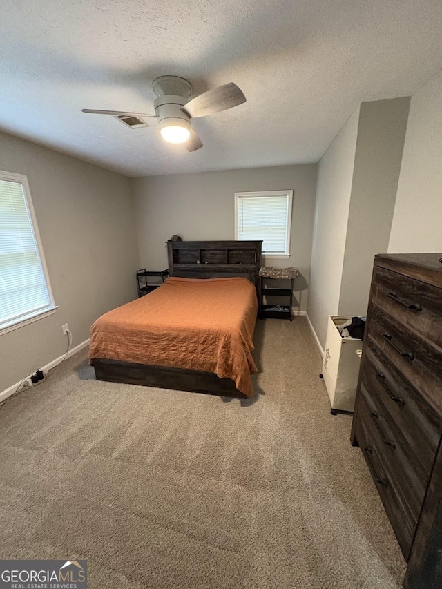 carpeted bedroom with visible vents, a textured ceiling, baseboards, and ceiling fan