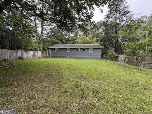 rear view of house with a lawn, a fenced backyard, and crawl space