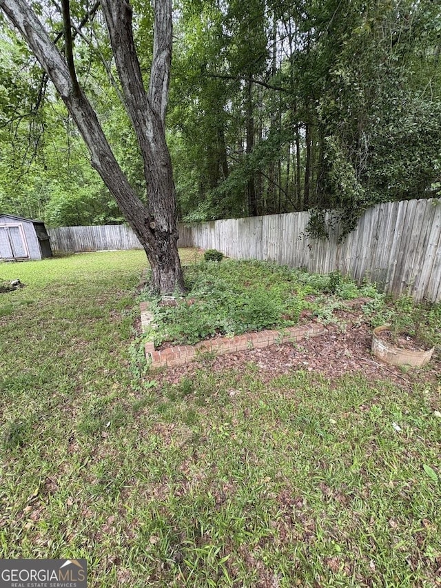 view of yard with an outdoor structure, a fenced backyard, and a shed