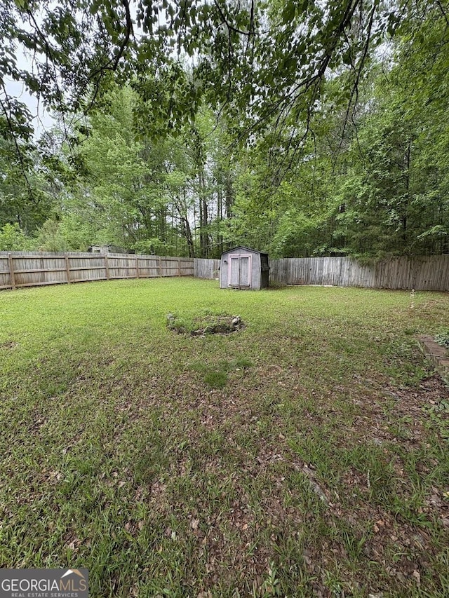 view of yard featuring an outbuilding, a fenced backyard, and a storage unit