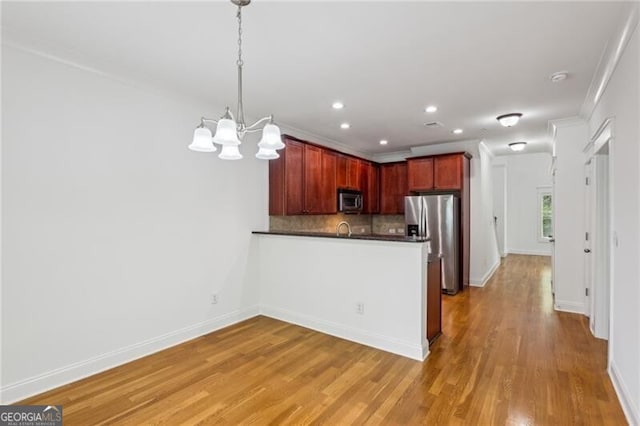 655 Mead St SE Unit 58, Atlanta, GA 30312 - kitchen featuring appliances with stainless steel finishes, dark countertops, a peninsula, a chandelier, and tasteful backsplash