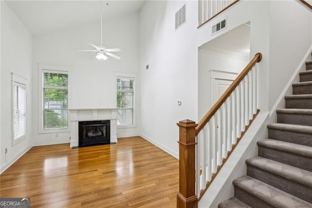 655 Mead St SE Unit 58, Atlanta, GA 30312 - unfurnished living room with a towering ceiling, stairway, light wood-style flooring, a ceiling fan, and a fireplace with flush hearth
