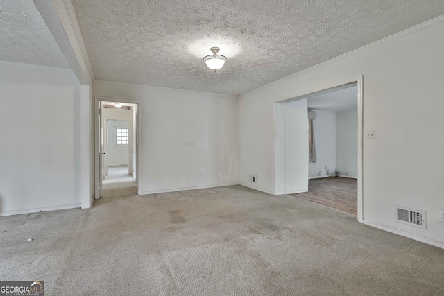 spare room featuring crown molding, carpet, a textured ceiling, and visible vents