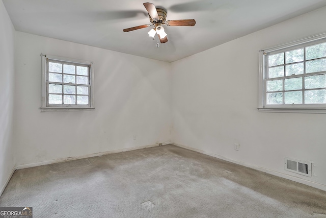 unfurnished room with light colored carpet, ceiling fan, visible vents, and a wealth of natural light