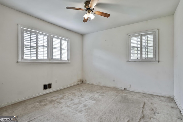 carpeted empty room featuring baseboards, a ceiling fan, and visible vents