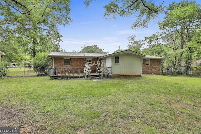 rear view of house with brick siding, fence, a yard, and a deck