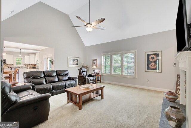 living room with baseboards, a ceiling fan, light carpet, and high vaulted ceiling