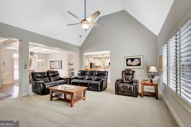 carpeted living room featuring high vaulted ceiling and ceiling fan with notable chandelier