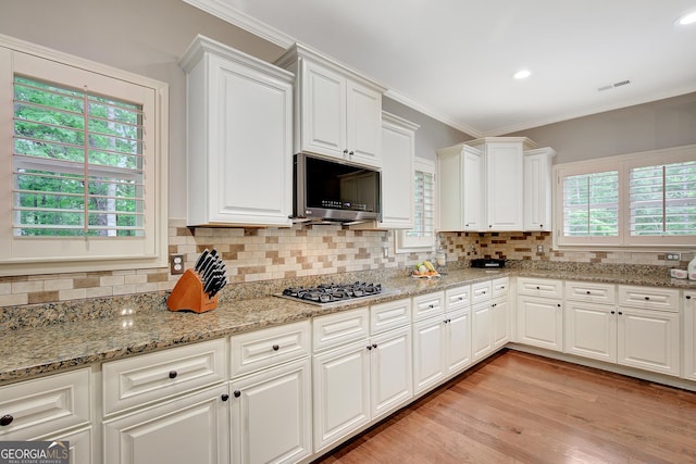 kitchen featuring crown molding, white cabinets, tasteful backsplash, and stainless steel appliances