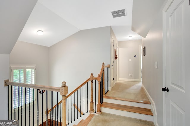 stairs with carpet floors, baseboards, visible vents, and lofted ceiling