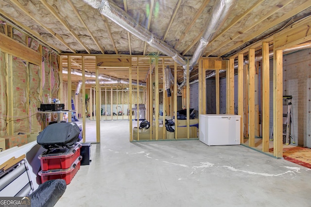 unfinished basement featuring refrigerator