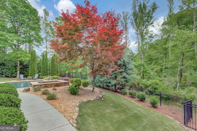 view of home's community featuring a yard, a forest view, and fence