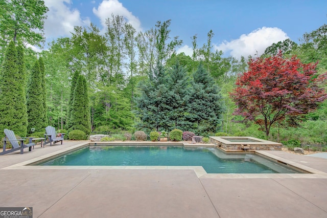 pool with a patio and an in ground hot tub