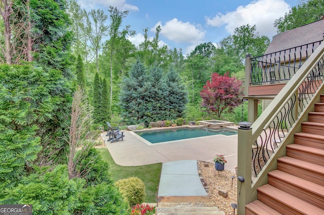 outdoor pool with stairs, an in ground hot tub, a patio area, and a wooden deck