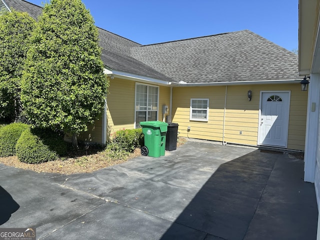 exterior space with roof with shingles and a patio