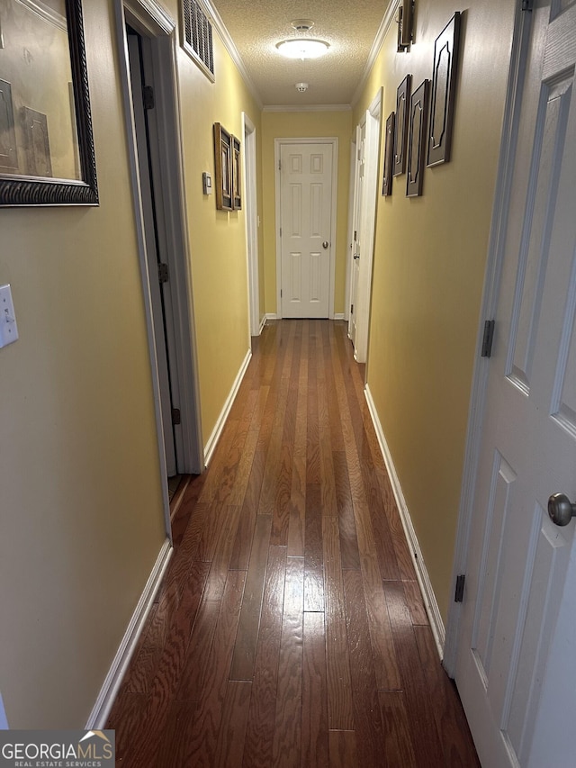 hall with crown molding, baseboards, visible vents, and dark wood-style floors