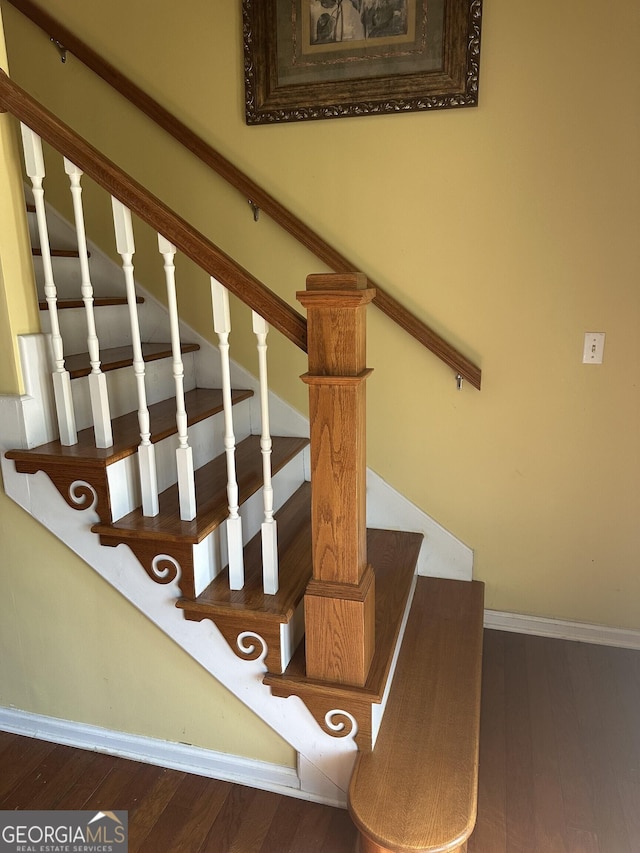 staircase featuring baseboards and wood finished floors
