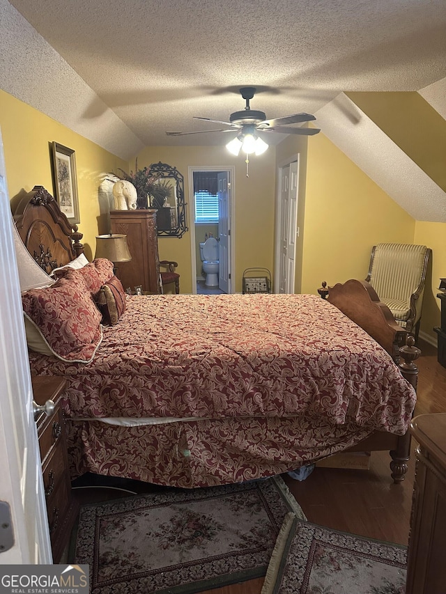 bedroom with a ceiling fan, a textured ceiling, wood finished floors, connected bathroom, and lofted ceiling