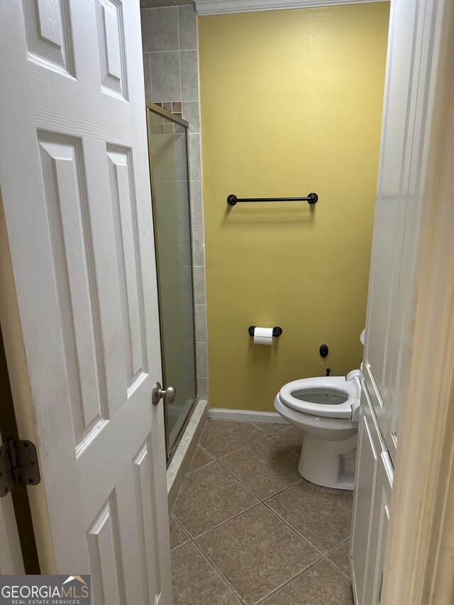 bathroom featuring tile patterned flooring, baseboards, a stall shower, and toilet