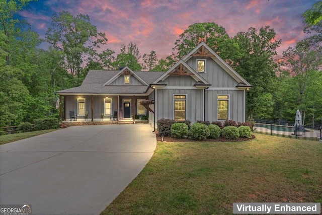craftsman-style home with board and batten siding, fence, covered porch, and a front yard