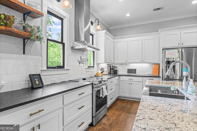 kitchen featuring visible vents, wall chimney exhaust hood, tasteful backsplash, a sink, and stainless steel appliances