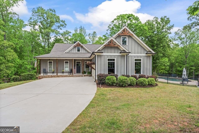 craftsman inspired home with board and batten siding, a porch, a fenced in pool, fence, and a front lawn