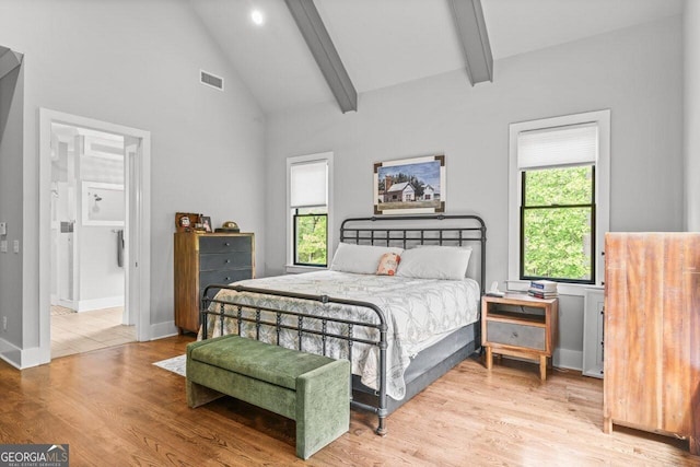 bedroom featuring multiple windows, beam ceiling, wood finished floors, and visible vents