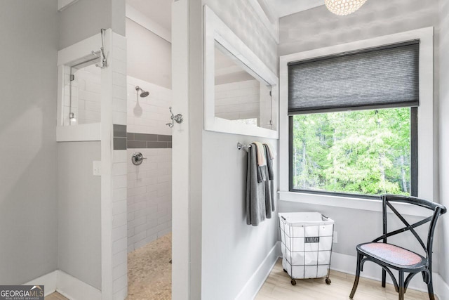 bathroom with baseboards, tiled shower, and wood finished floors