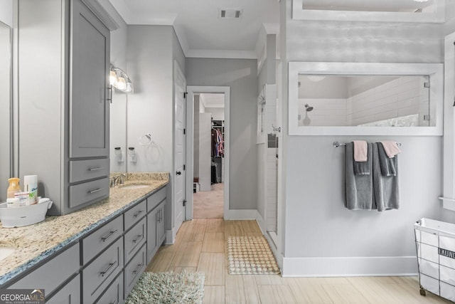 full bathroom featuring visible vents, double vanity, a walk in shower, and a sink