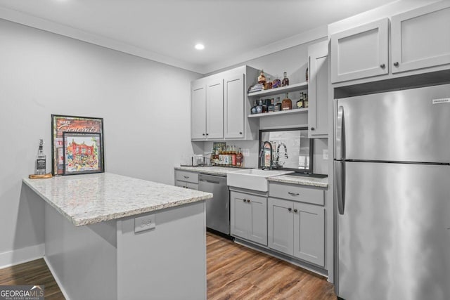 kitchen featuring open shelves, appliances with stainless steel finishes, light stone countertops, a sink, and dark wood finished floors
