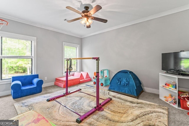 playroom with baseboards, crown molding, carpet, and ceiling fan