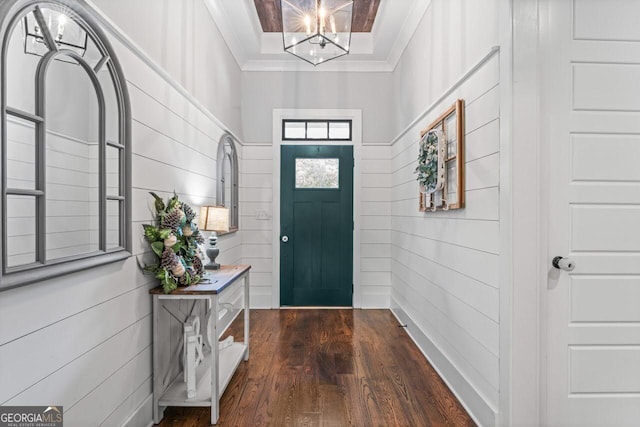 foyer entrance with dark wood-style flooring, an inviting chandelier, and ornamental molding