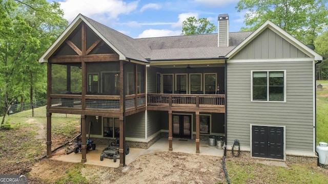 back of property with roof with shingles, french doors, a sunroom, board and batten siding, and a patio area