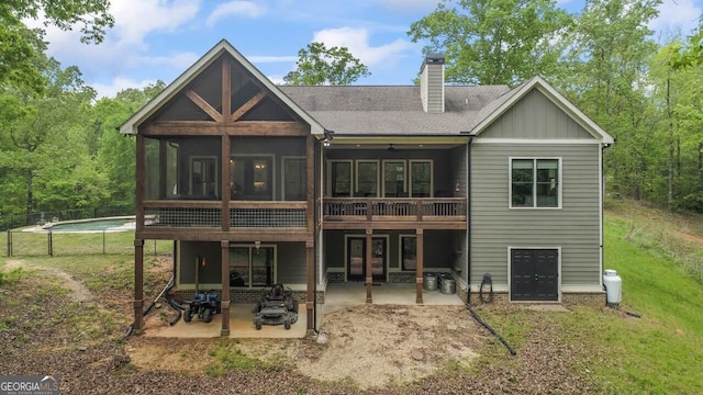 rear view of house featuring roof with shingles, a chimney, a sunroom, a patio area, and a lawn