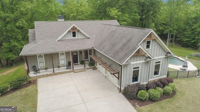 view of front of house featuring board and batten siding, covered porch, driveway, roof with shingles, and fence