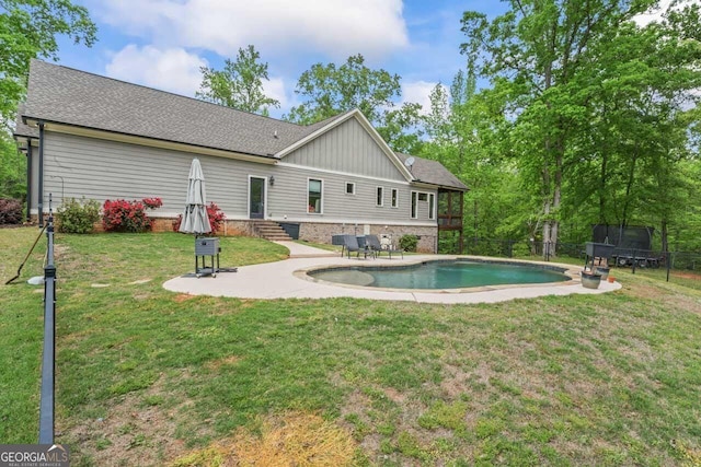back of property featuring fence, a patio, an outdoor pool, board and batten siding, and a yard