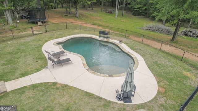 view of pool featuring fence, a trampoline, and a yard