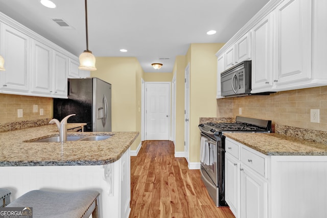 kitchen featuring a sink, white cabinetry, light wood-style floors, and appliances with stainless steel finishes