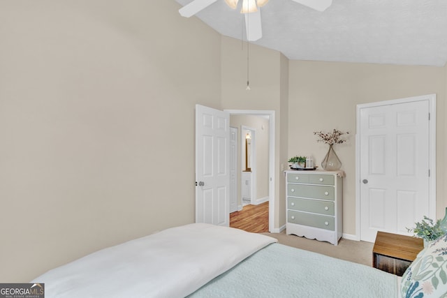 bedroom with vaulted ceiling, light carpet, baseboards, and a ceiling fan